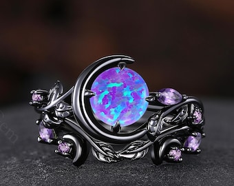 May include: Black ring with a crescent moon design and a large iridescent opal gemstone. The ring is adorned with smaller purple gemstones and intricate floral details.