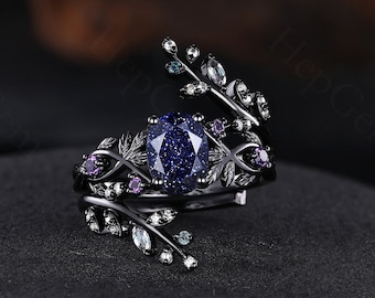 May include: A black ring with a large blue gemstone surrounded by smaller gemstones and intricate leaf designs.
