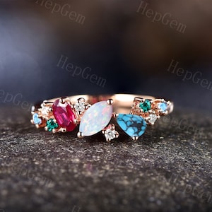 May include: A rose gold ring featuring an array of colourful gemstones, including a large opal, a ruby, turquoise, and emeralds. The ring is set with small diamonds.