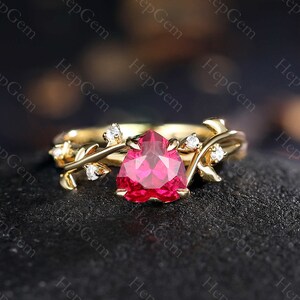 May include: A gold ring featuring a heart-shaped ruby gemstone and delicate vine accents with small diamonds.