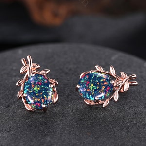 May include: A pair of rose gold earrings with a delicate leaf design and a round opal stone in the center. The opal stone has a blue, green, and red iridescent shimmer.