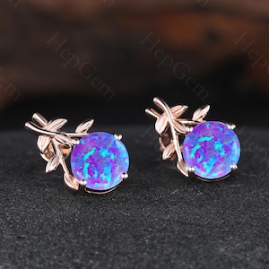 Puede incluir: Un par de pendientes de botón de oro rosa. Cada pendiente presenta una piedra preciosa de ópalo azul vibrante y redonda con un patrón arremolinado. Las piedras preciosas están engastadas en un delicado diseño en forma de hoja.