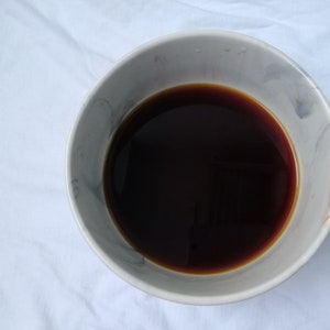 May include: A white ceramic bowl with a gray marbled design filled with dark brown liquid.