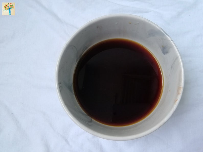 May include: A white ceramic bowl with a gray marbled design filled with dark brown liquid.