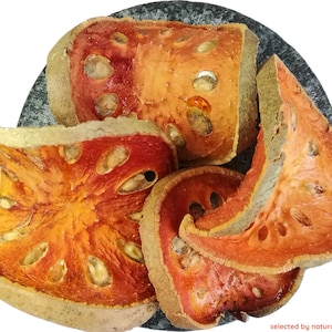 Peut inclure: Tranches séchées de fruit de bael, également appelé pomme de bois, sur une surface en pierre grise. Les tranches de fruits sont d'une couleur orange-rouge vif avec un bord extérieur brun clair. Le fruit a une saveur distinctive, légèrement sucrée et acidulée.