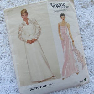 May include: Vogue Patterns Paris Original sewing pattern featuring two elegant dress designs by Pierre Balmain. The pattern envelope shows illustrations of a white lace-sleeved gown and a pink strapless dress. The pattern number is 2835.