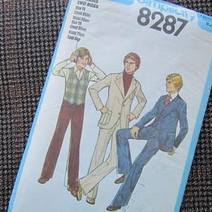 May include: A vintage Simplicity 8287 sewing pattern with illustrations of men's suits. The pattern includes measurements for two sizes: Chest 81cm, Waist 60cm, and Chest 85cm, Waist 71cm. The pattern is on a blue background.