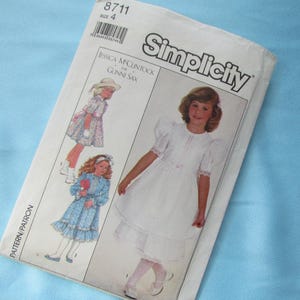 May include: A Simplicity sewing pattern envelope, number 8711, size 4, featuring Jessica McClintock for Gunne Sax designs. The white paper envelope displays illustrations of children wearing white and blue dresses with puff sleeves and lace trim.