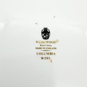 May include: White bone china with the text "WEDGWOOD" and "Bone China MADE IN ENGLAND". The text "COLUMBIA W595" is also visible. The Wedgwood logo is a black silhouette of a vase with a decorative design.