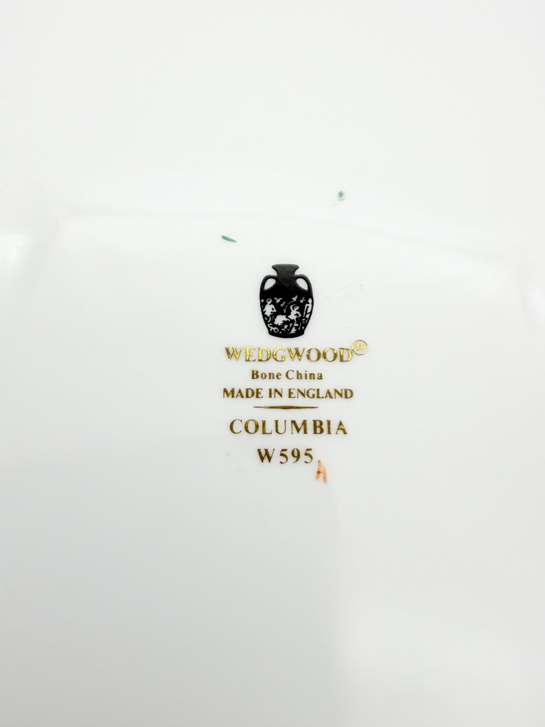 May include: White bone china with the text "WEDGWOOD" and "Bone China MADE IN ENGLAND". The text "COLUMBIA W595" is also visible. The Wedgwood logo is a black silhouette of a vase with a decorative design.