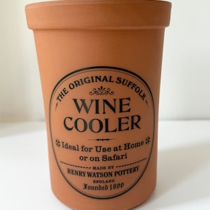 May include: Terracotta wine cooler with a black label that reads "The Original Suffolk Wine Cooler. Ideal for Use at Home or on Safari. Made by Henry Watson Pottery, England. Founded 1800."