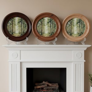 May include: Three circular wall art pieces featuring a forest landscape painting with tall green trees and light filtering through the canopy. Each piece is encased in a round wooden frame, with one dark brown, one medium brown, and one light tan finish.