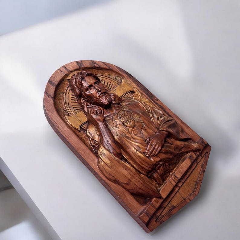 Op de afbeelding: Een houten wandplaquette met een gegraveerd beeld van Jezus Christus met een gouden hart op zijn borst. De plaquette is gemaakt van donker hout met een gouden rand.