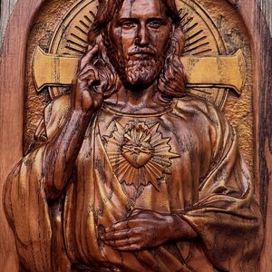Op de afbeelding: Een houten beeldhouwwerk van Jezus Christus met een gouden hart op zijn borst. Het beeldhouwwerk is gedetailleerd en realistisch, met een warme bruine houtkleur.
