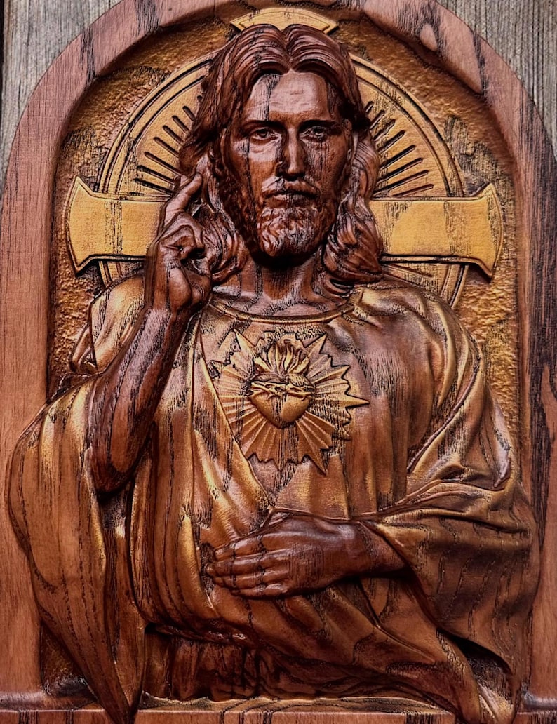 Op de afbeelding: Een houten beeldhouwwerk van Jezus Christus met een gouden hart op zijn borst. Het beeldhouwwerk is gedetailleerd en realistisch, met een warme bruine houtkleur.