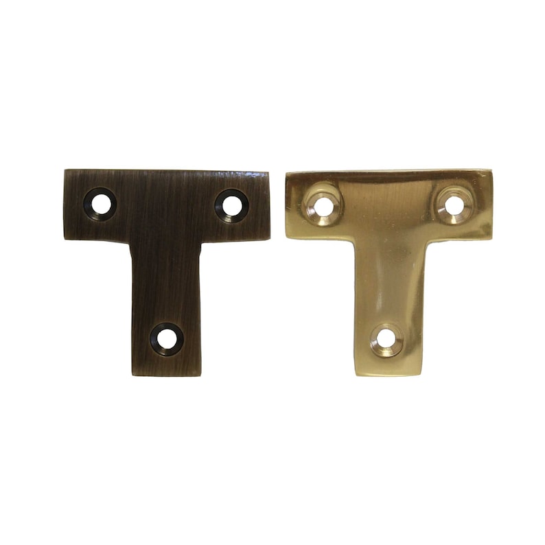 May include: Two T-shaped metal shelf brackets, one in a brushed brass finish and one in a polished brass finish.