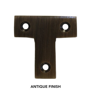 May include: Antique brass T-shaped shelf bracket with three holes for mounting.  The bracket has a brushed finish.