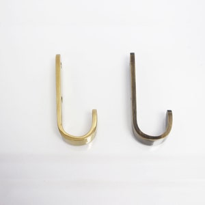 May include: Two metal hooks, one gold and one antique brass, with a curved design.