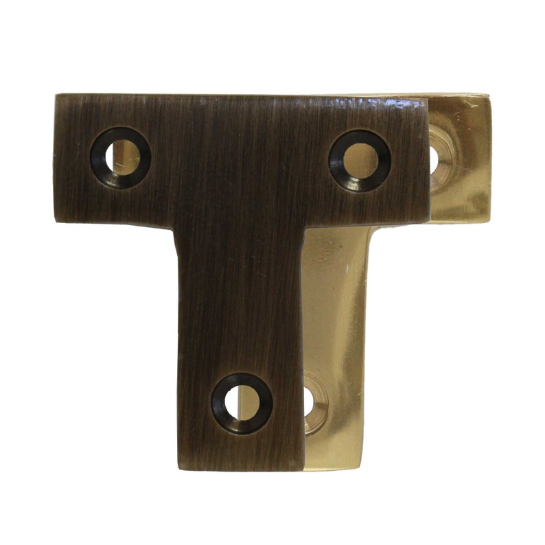 May include: A T-shaped metal bracket with two holes on the top and one hole on the bottom. The bracket is made of brass and has a brushed finish.