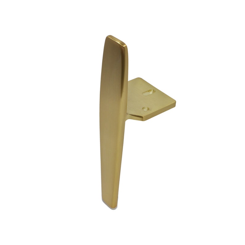 May include: A gold-toned metal cabinet pull with a long, narrow, rectangular handle and a square base.