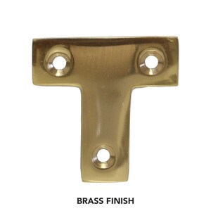 May include: A brass T-shaped shelf bracket with three screw holes.  BRASS FINISH.