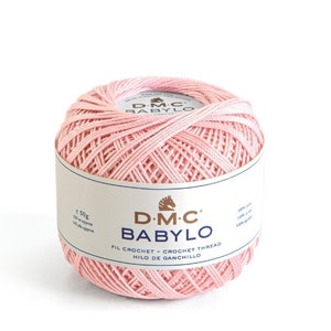 Peut inclure: Une pelote de fil à crocheter DMC Babylo de couleur rose. L'étiquette indique "D-M-C BABYLO FIL CROCHET - CROCHET THREAD HILO DE GANCHILLO" et présente un logo de cheval. La pelote pèse 50 grammes et mesure 133 mètres.