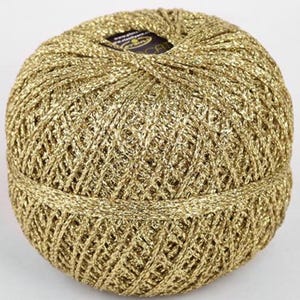 Può includere: Un gomitolo di filo metallico dorato con un'etichetta che dice "DMC Natura Just Cotton".