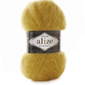 May include: A ball of Alize Classic mohair yarn in a golden yellow hue. The yarn is wrapped with a black label featuring the brand name and logo. The yarn appears soft and fluffy, ideal for knitting or crocheting projects.
