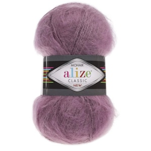 May include: A ball of lavender mohair yarn with a black and silver label. The label reads "MOHAIR alize CLASSIC NEW" in white and green text. The yarn is fluffy and soft, suitable for knitting or crochet projects.