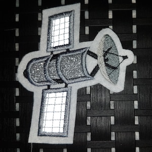 Könnte beinhalten: Ein weißer gestickter Aufnäher, der einen Satelliten mit einer großen Parabolantenne und zwei Solarpaneelen zeigt. Der Satellit ist schwarz umrandet und hat ein Grau-Weiß-Farbschema.