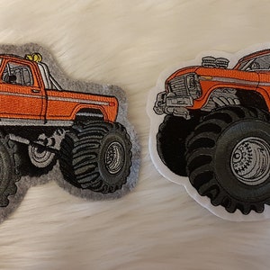 Könnte beinhalten: Zwei gestickte Aufnäher mit einem orangefarbenen Monstertruck mit großen schwarzen Reifen. Der Truck befindet sich auf einem grauen Hintergrund links und einem weißen Hintergrund rechts.