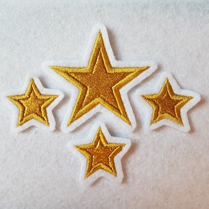 Könnte beinhalten: Fünf goldene sternförmige Patches auf weißem Hintergrund. Die Sterne sind unterschiedlich groß und haben eine leicht erhabene, strukturierte Oberfläche.