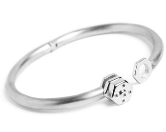 May include: A silver bracelet featuring a hexagonal design and a small nut on the side.