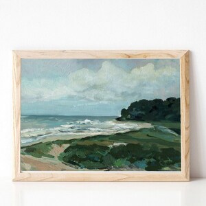May include: A framed painting of a seascape with a green grassy shore, blue water, and white clouds in the sky.