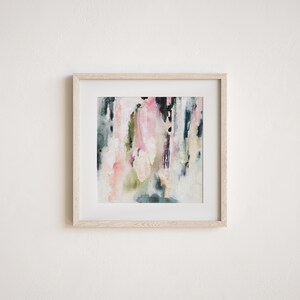 May include: Abstract watercolor painting in a light wood frame. The painting features shades of pink, green, and blue with white accents.