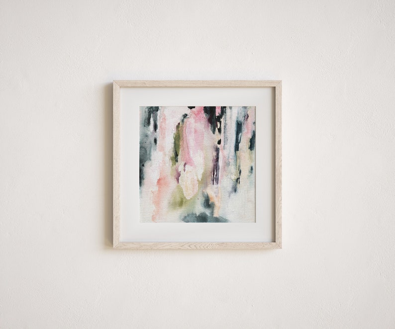 May include: Abstract watercolor painting in a light wood frame. The painting features shades of pink, green, and blue with white accents.