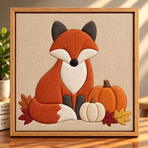 Könnte beinhalten: Ein gerahmtes Wandbild aus Stoff mit einem stilisierten Fuchs aus orangefarbenen, weißen und dunkelgrauen Stoffteilen. Der Fuchs sitzt neben einem großen orangefarbenen Kürbis, einem kleineren weißen Kürbis und mehreren Stoffblättern.