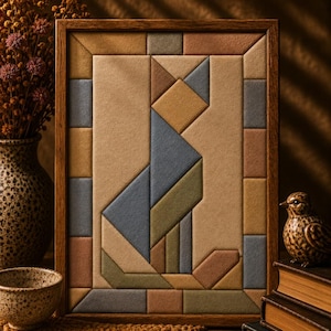 May include: A rectangular wooden-framed wall art piece featuring a geometric mosaic of a cat. The design is composed of various fabric-covered shapes in muted tones of tan, blue, olive green, and brown, arranged to form a stylised feline silhouette.