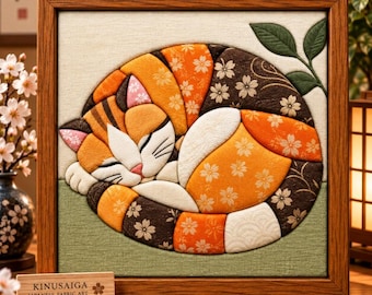 May include: A framed Kinusaiga Japanese fabric art piece depicting a curled-up calico cat. The cat is composed of orange, white, and dark brown fabric patches with floral patterns. A small wooden sign in front reads KINUSAIGA JAPANESE FABRIC ART.