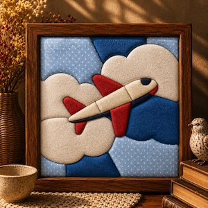 May include: A square framed fabric wall art piece featuring a layered textile collage of an airplane flying through clouds. The airplane is cream and red, set against a background of blue polka dot fabric and solid dark blue and cream fabric clouds.