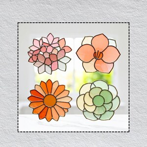May include: Four stained glass flower decorations in shades of pink, orange, and green. Each flower has a unique design, with petals and centers in varying colors. The glass is outlined in a dark color.