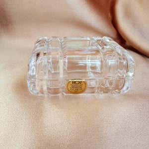 Puede incluir: Una caja rectangular de vidrio transparente con una etiqueta dorada que dice "RCR Royal Crystal Rock Genuine Lead Crystal Over 24% PbO Made in Italy".
