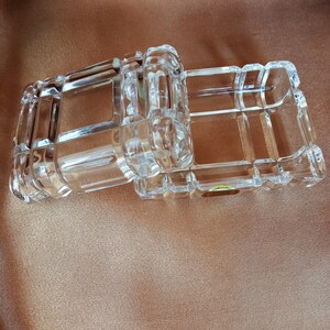 May include: Two clear glass boxes with a decorative, geometric pattern. The boxes are stacked on top of each other.
