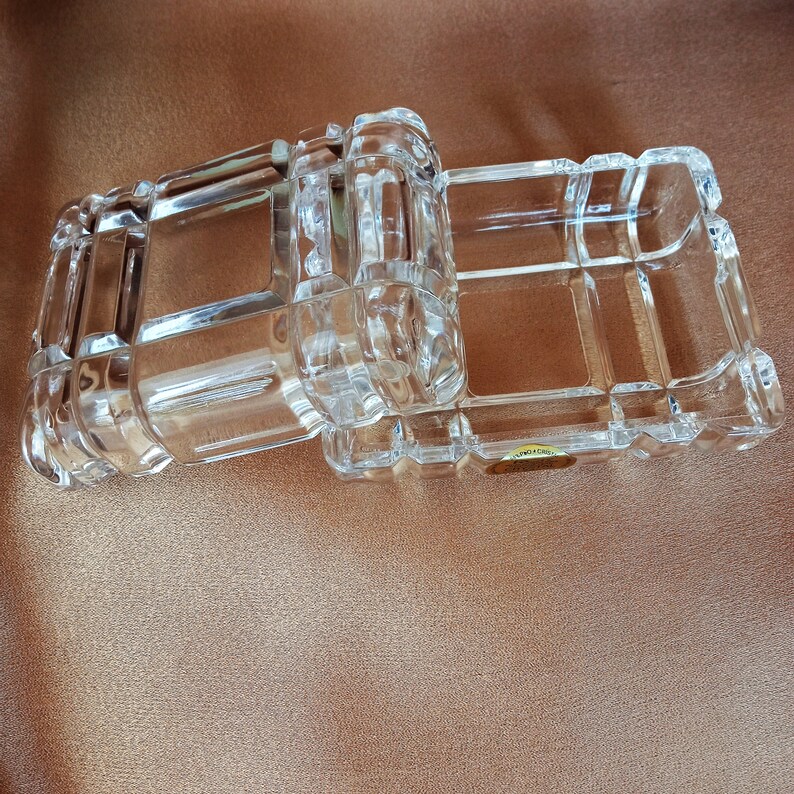 May include: Two clear glass boxes with a decorative, geometric pattern. The boxes are stacked on top of each other.
