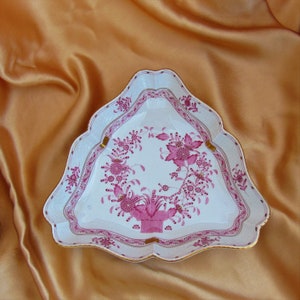 May include: A white porcelain triangular dish with a pink floral design. The dish has a scalloped edge and a raised rim.