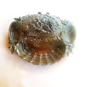 May include: A vintage bronze trinket box with a floral design and a hinged lid. The box is shaped like a shell and has intricate details.