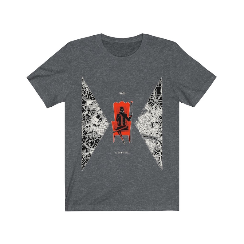 Op de afbeelding: Een donker grijs t-shirt met een zwart-witte afbeelding van een persoon die op een rode troon zit met een kaartontwerp op de achtergrond. De tekst "The Devil" is onder de afbeelding gedrukt.