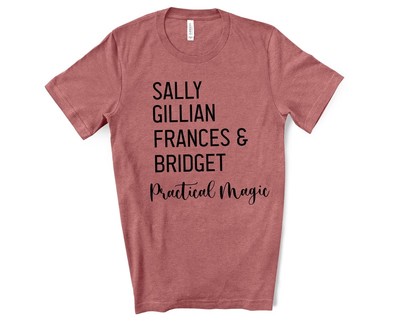 Peut inclure: Un t-shirt rose poussi&eacute;reux avec les noms "SALLY", "GILLIAN", "FRANCES &", "BRIDGET" imprim&eacute;s en noir, empil&eacute;s verticalement. Les mots "Practical Magic" sont &eacute;crits en cursive en dessous.