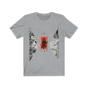 Op de afbeelding: Een grijs T-shirt met een zwart-wit ontwerp van een stadskaart. Het ontwerp toont een silhouet van een persoon die op een rode troon zit, een kroon draagt en een scepter vasthoudt. De tekst "ANARCHY" is onder de troon gedrukt.