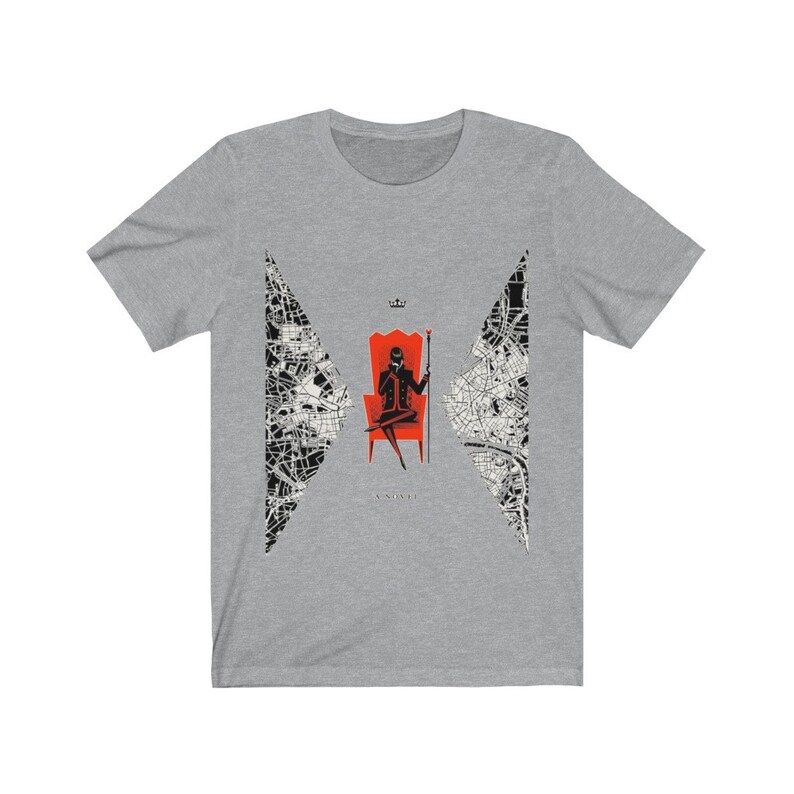 Op de afbeelding: Een grijs T-shirt met een zwart-wit ontwerp van een stadskaart. Het ontwerp toont een silhouet van een persoon die op een rode troon zit, een kroon draagt en een scepter vasthoudt. De tekst "ANARCHY" is onder de troon gedrukt.